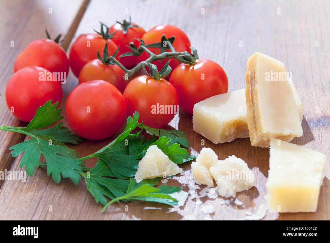Parmasian vined Tomaten, Käse und Petersilie Schuß im Sonnenlicht auf Holztisch, italienischen Zutaten Stockfoto