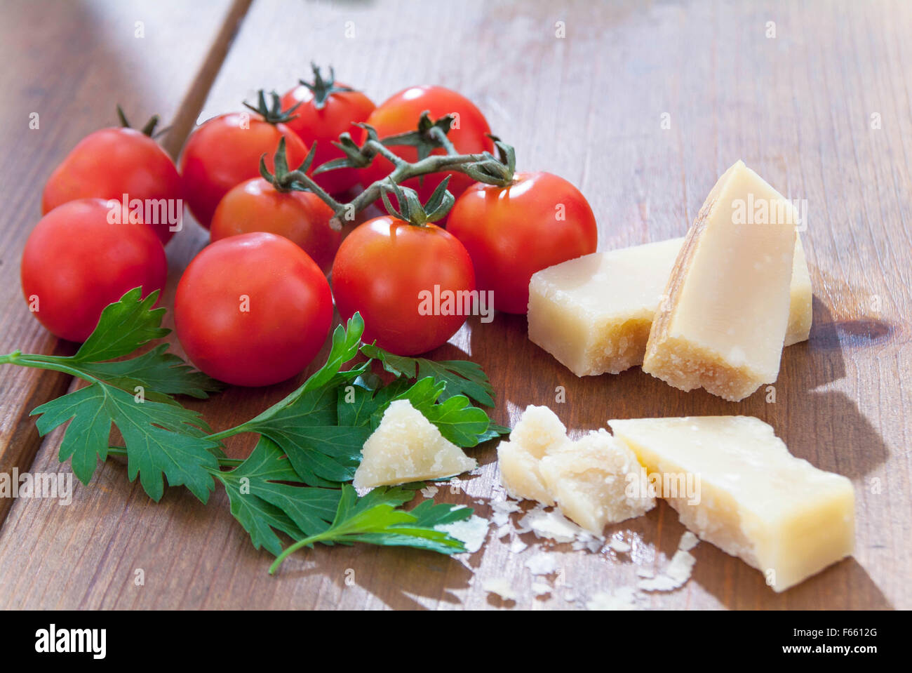 Parmasian vined Tomaten, Käse und Petersilie Schuß im Sonnenlicht auf Holztisch, italienischen Zutaten Stockfoto