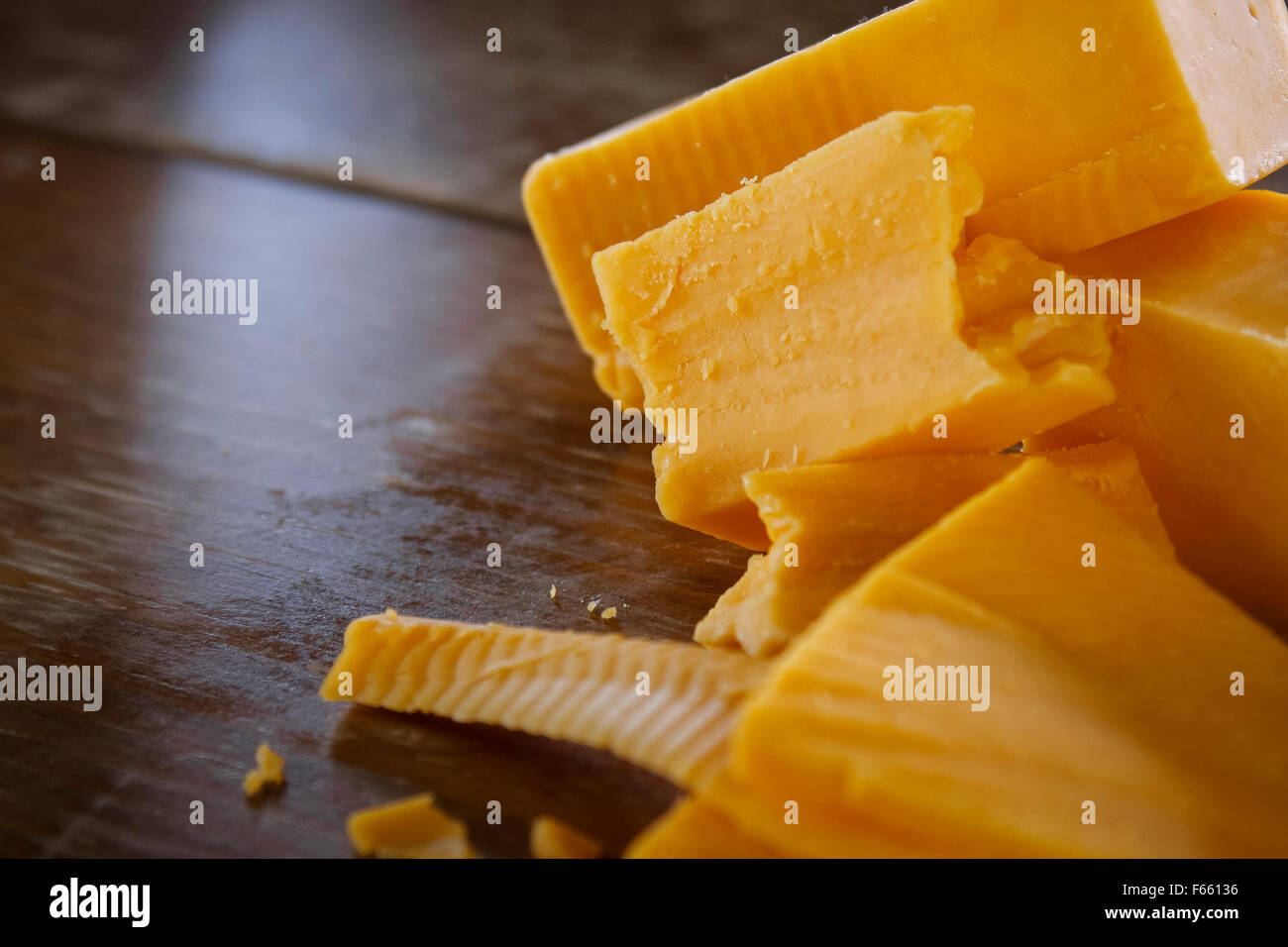 Scheiben, Blöcke und ein Ziegelstein des goldenen Käse auf dem Holztisch. Stockfoto