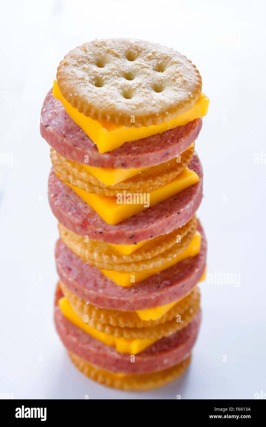 Turm von gestapelten Cracker, Käse und Salami auf weißem Hintergrund. Stockfoto