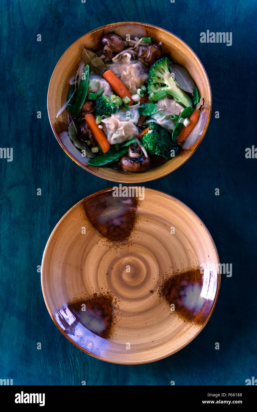 Ansicht von oben aus Keramik Schüssel und Teller mit Suppe, Eintopf auf einem grünlich-blau Holzmaserung Stockfoto