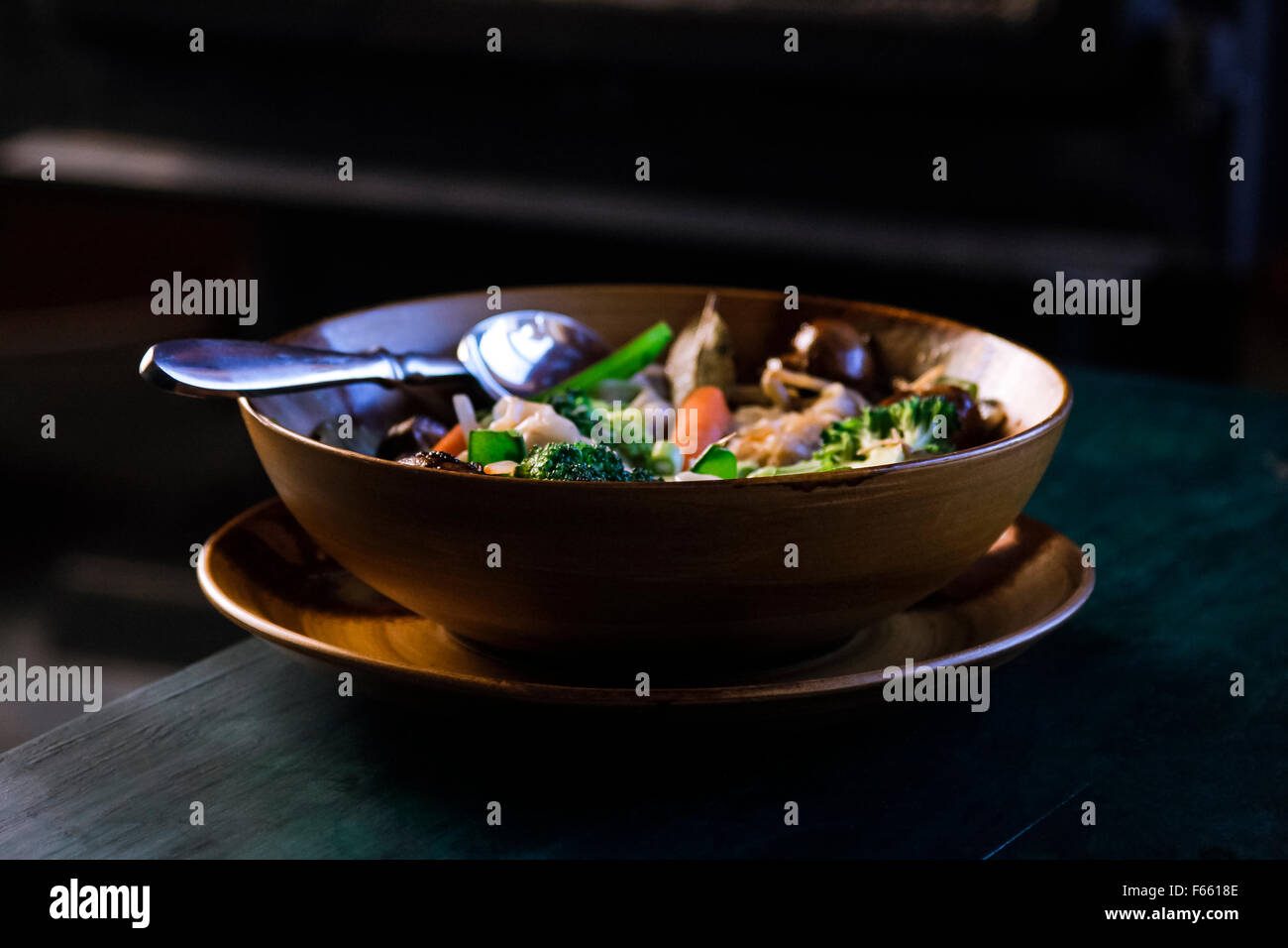 Blick auf Gemüse Suppe oder Eintopf in einem braun oder hellbraun Schüssel in einem Teller, auf einem grünlich-blau Holz Korn in der rustikalen Umgebung Stockfoto
