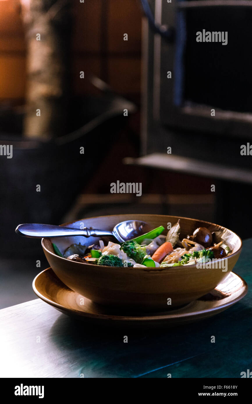 Blick auf Gemüse Suppe oder Eintopf in einem braun oder hellbraun Schüssel in einem Teller, auf einem grünlich-blau Holz Korn in der rustikalen Umgebung Stockfoto