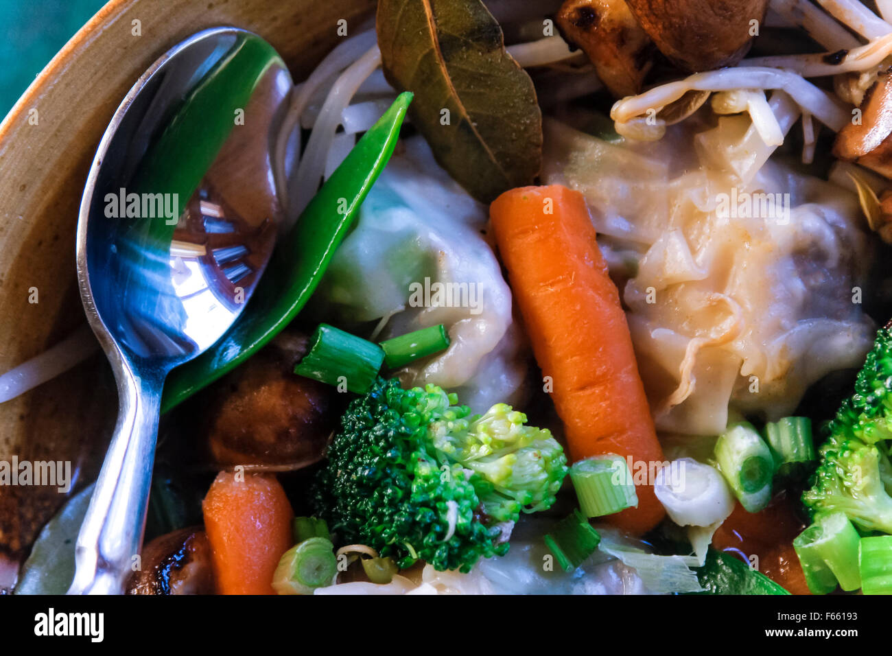 Close-up Löffel, Karotte Brokkoli und Champignons in einer braunen Keramik Schüssel mit anderen Suppe Zutaten. Stockfoto