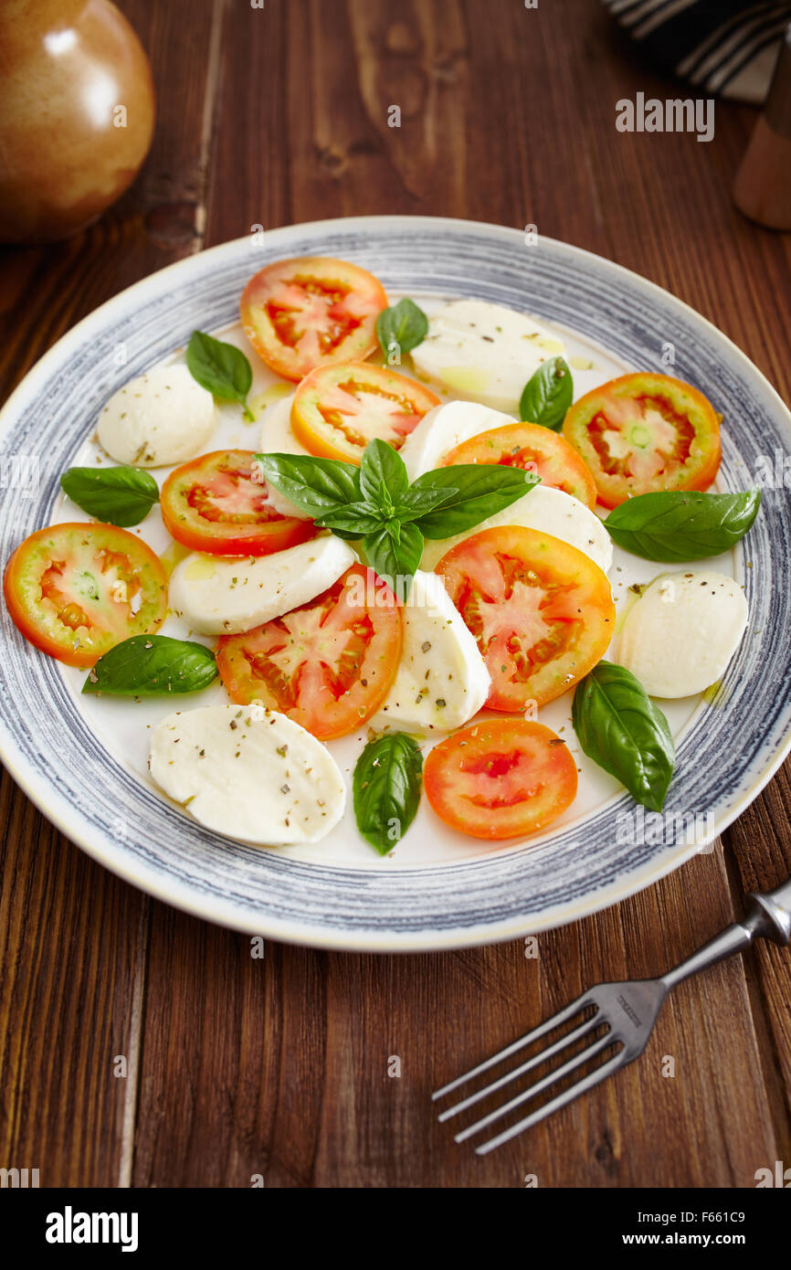 Caprese-Salat in einer blau Pastell Platte auf einem alten Holztisch, mit Salz und Pfeffer Stockfoto