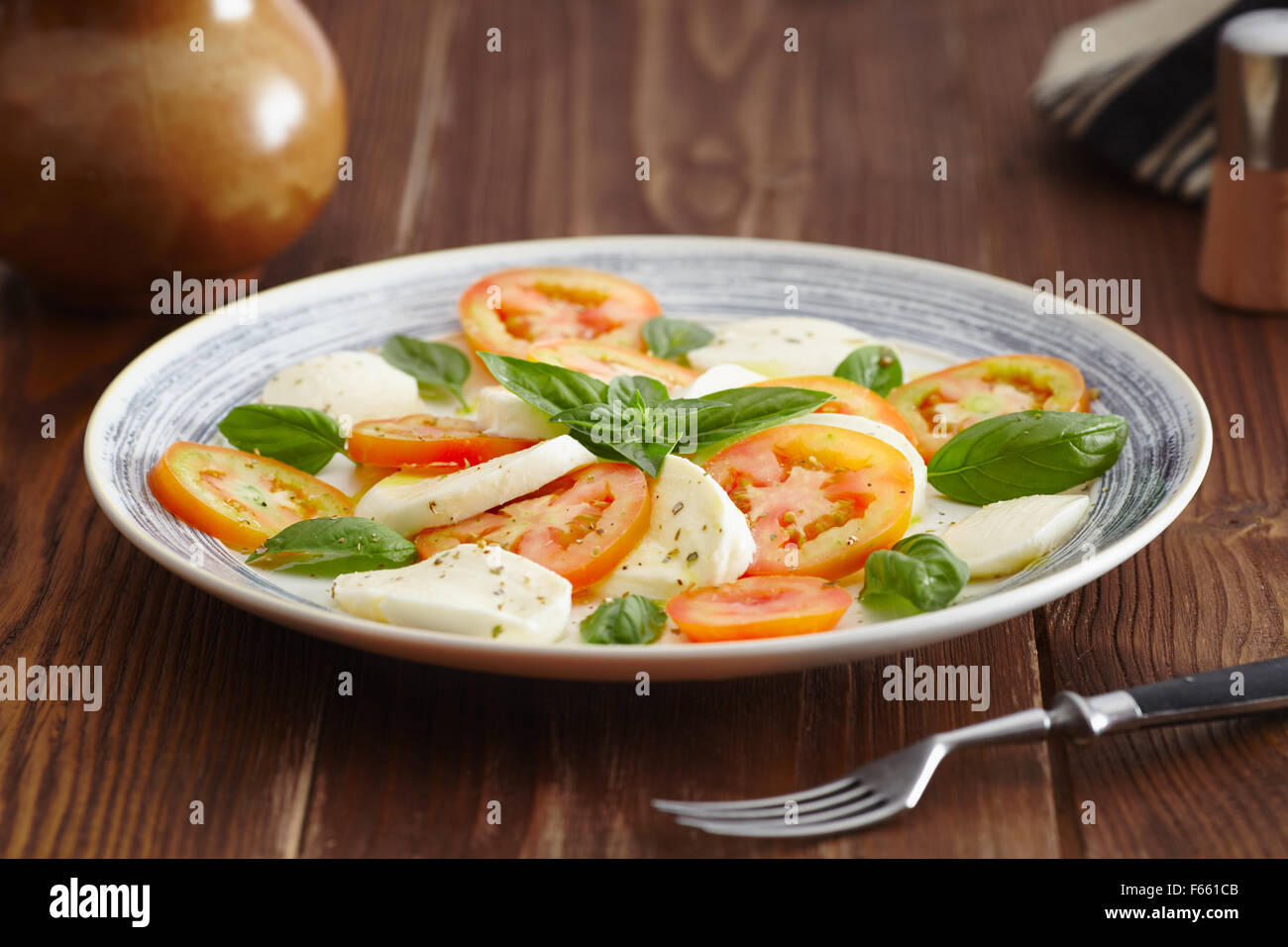 Caprese-Salat in einer blau Pastell Platte auf einem alten Holztisch, mit Salz und Pfeffer Stockfoto