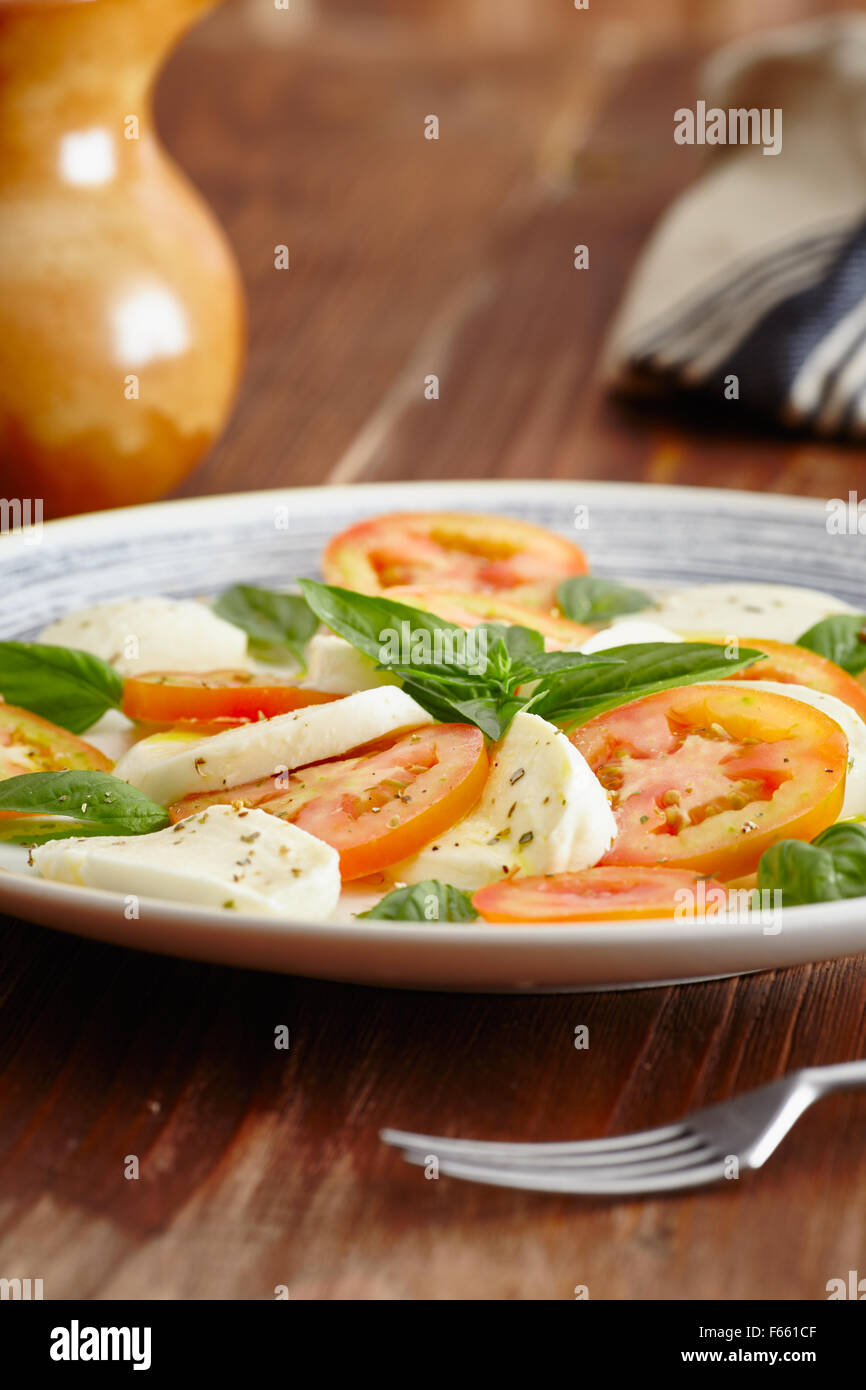 Caprese-Salat in einer blau Pastell Platte auf einem alten Holztisch, mit Salz und Pfeffer Stockfoto