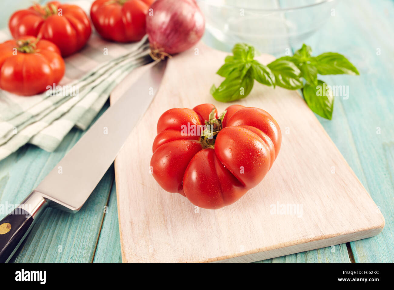 Tomaten-Corleone-Typ für Sauce auf einem Aqua Holztisch mit Basilikum und Zwiebeln Stockfoto