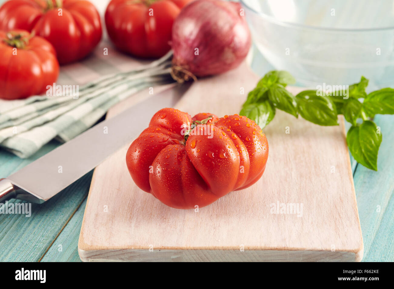Tomaten-Corleone-Typ für Sauce auf einem Aqua Holztisch mit Basilikum und Zwiebeln Stockfoto