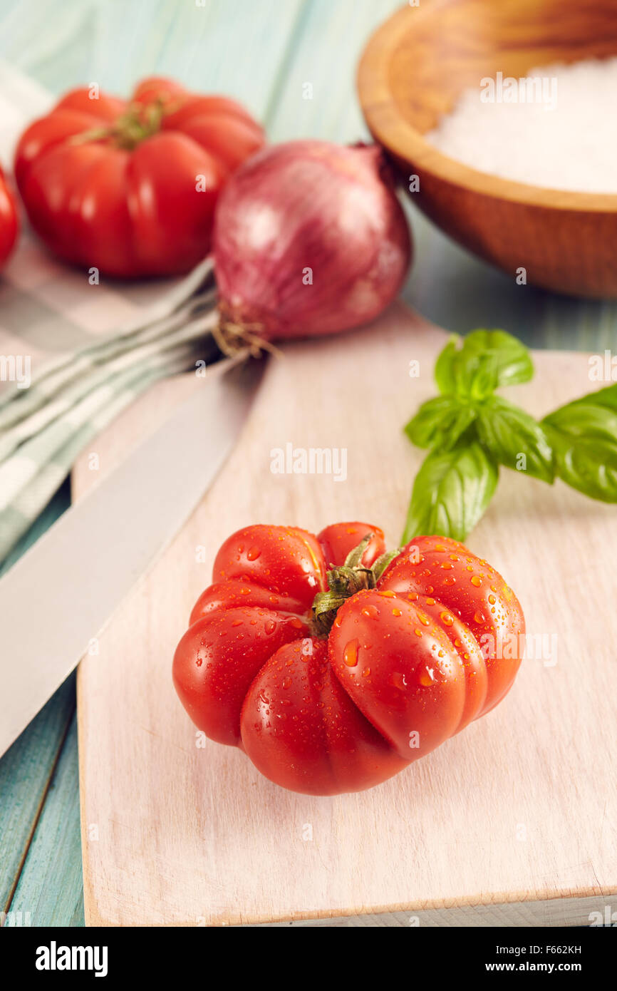 Tomaten-Corleone-Typ für Sauce auf einem Aqua Holztisch mit Basilikum und Zwiebeln Stockfoto