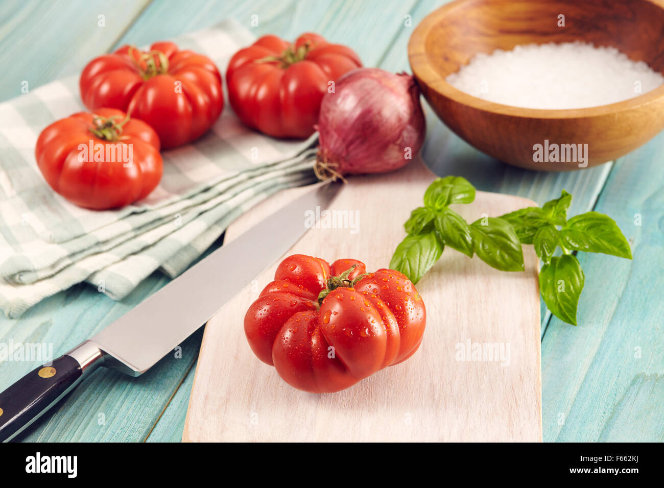 Tomaten-Corleone-Typ für Sauce auf einem Aquamarin Holztisch mit Basilikum und Zwiebeln Stockfoto