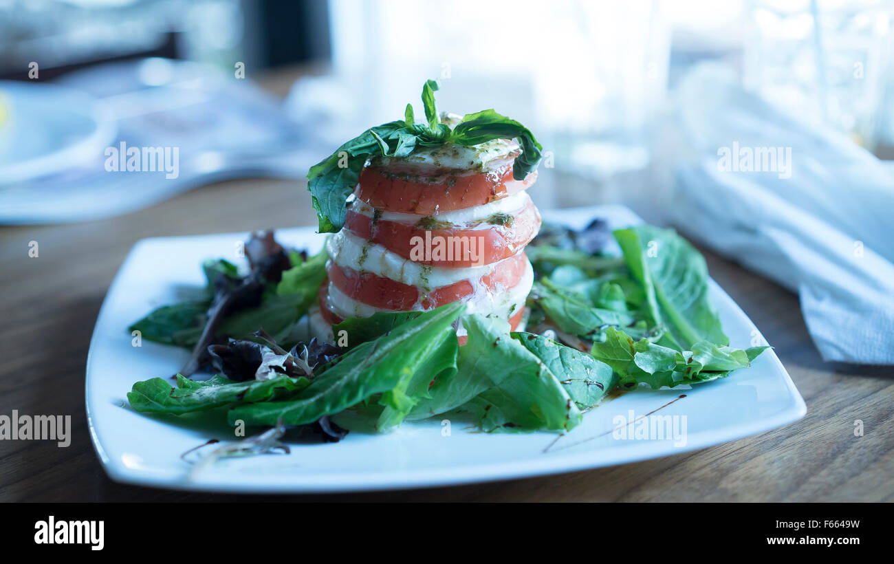 Vergoldete Caprese Salat mit Balsamico Nieselregen auf gemischten Salat Meskalin in saubere Küche mit Fenster Licht. Stockfoto