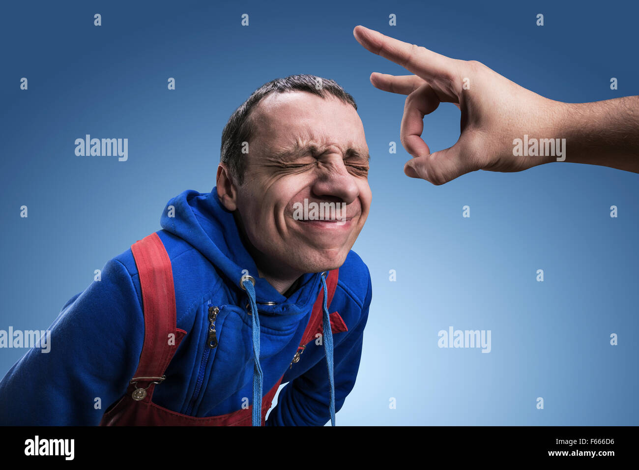 Ein junger Mann bekommt Ansporn auf seine Stirn gegen blau Stockfoto
