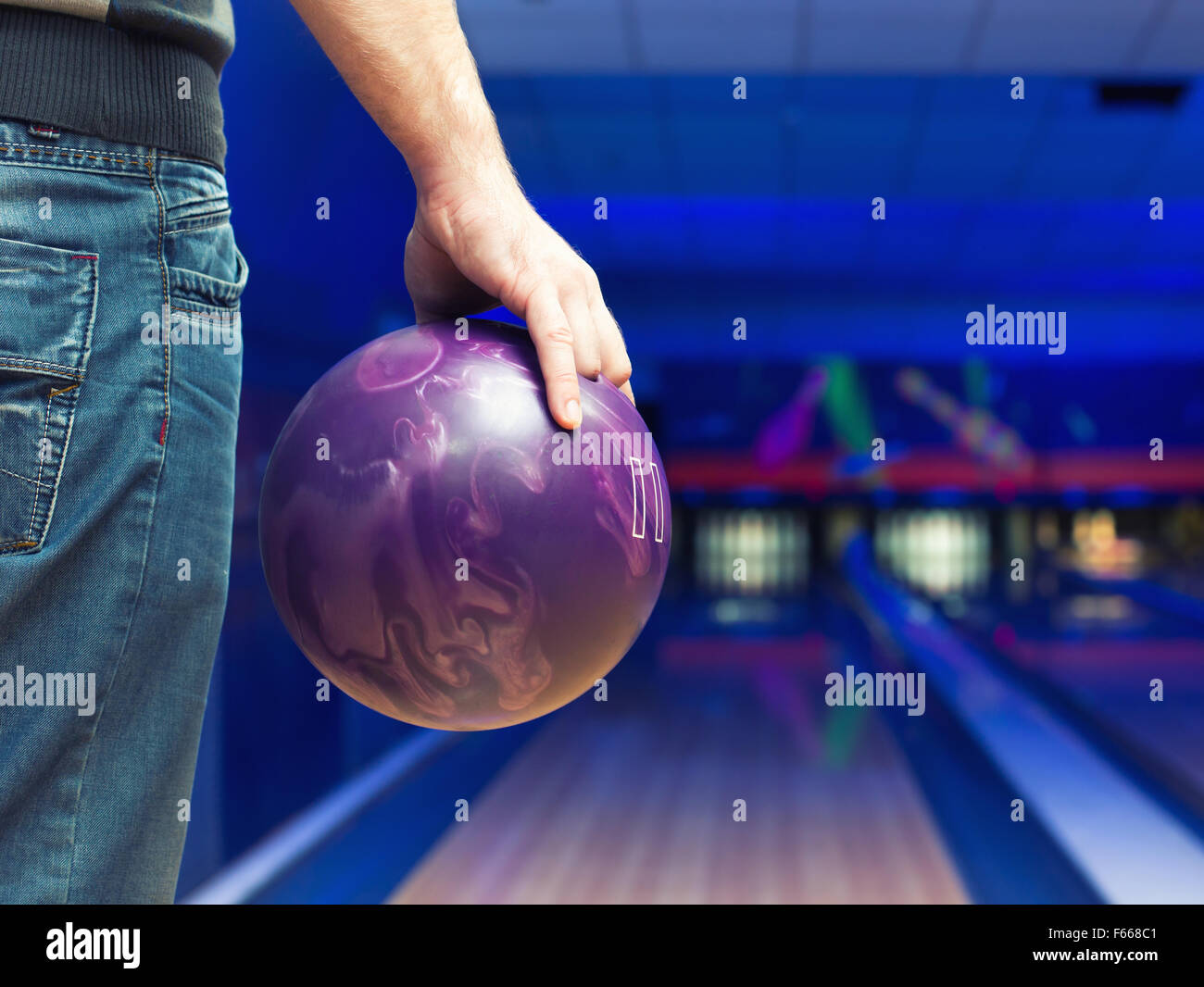 Mann mit Ball gegen Kegelbahn Stockfoto