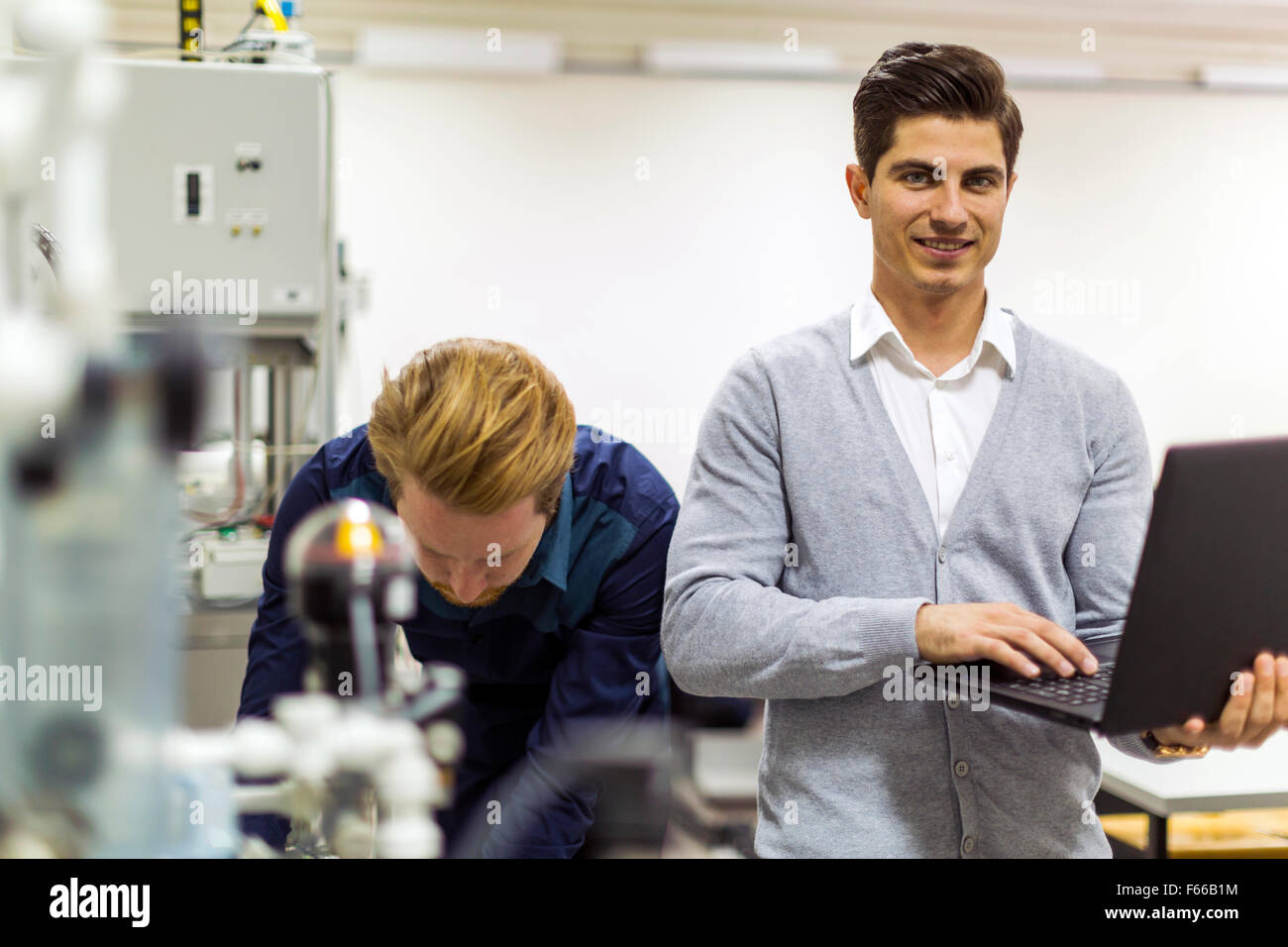 Porträt von Ayoung schön Ingenieur Überleitung der Daten auf einem Laptop und lächelnd Stockfoto