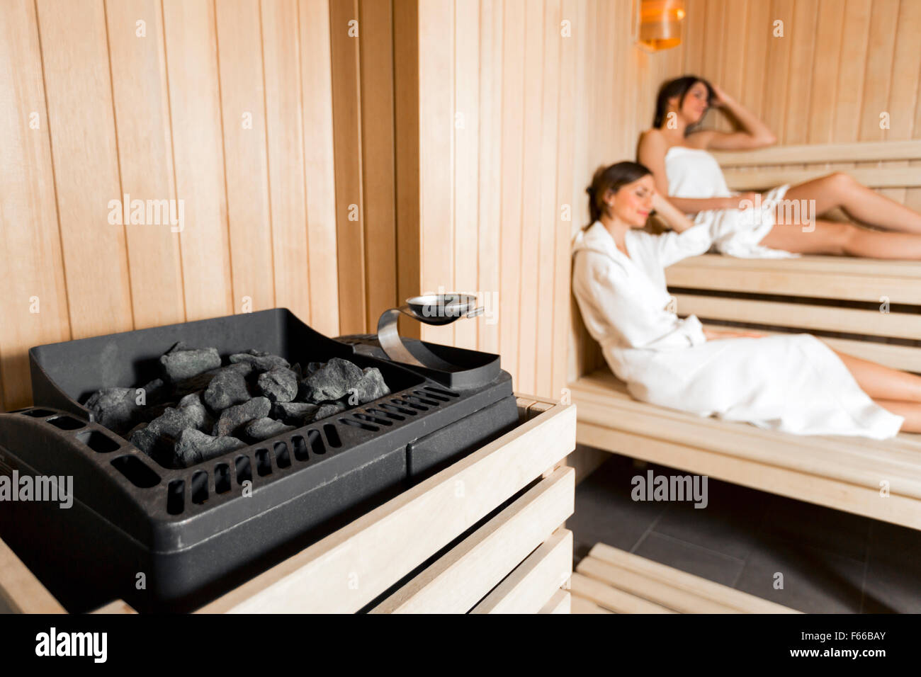 Saunaofen in eine gemütliche Sauna und Mädchen entspannen im Hintergrund Stockfoto