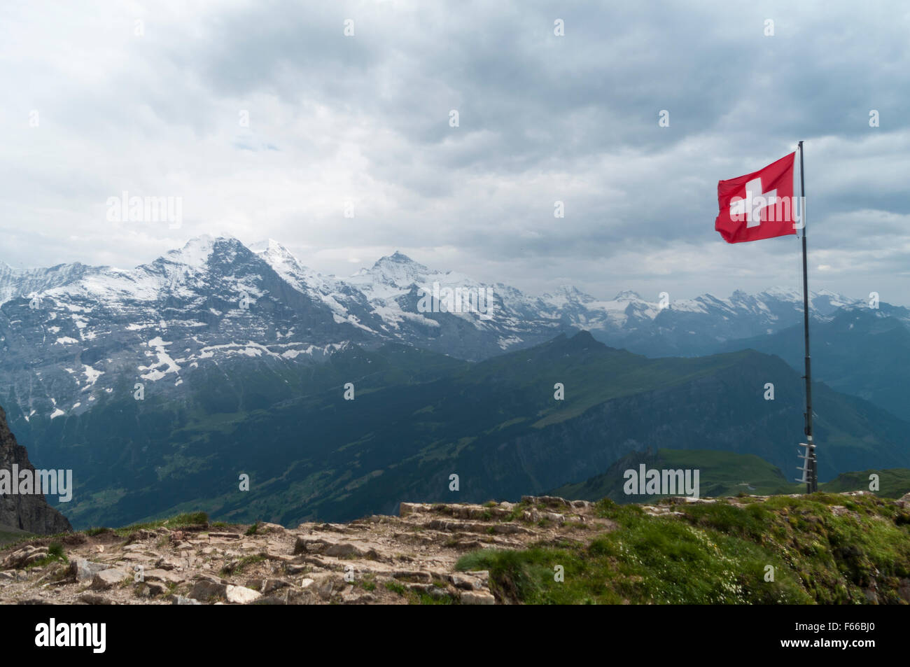 Schweizer Flagge bei starkem Wind. Schlechtes Wetter, Wolken, Regen. In den Hintergrund Eiger, Mönch und Jungfrau Bergen. Stockfoto