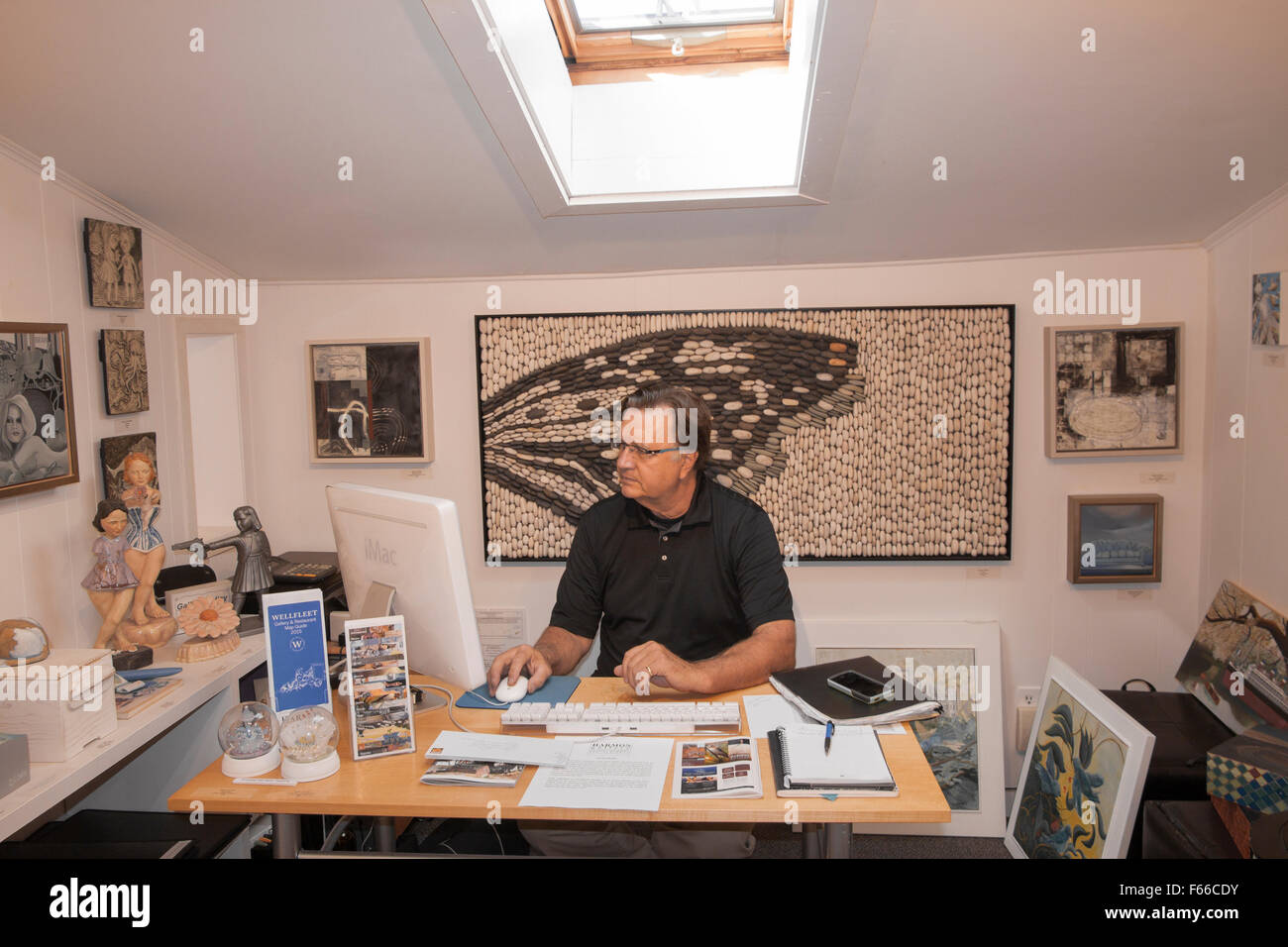 Kunst Galerie Besitzer/Künstler sitzt an seinem Schreibtisch arbeiten am Computer. Stockfoto