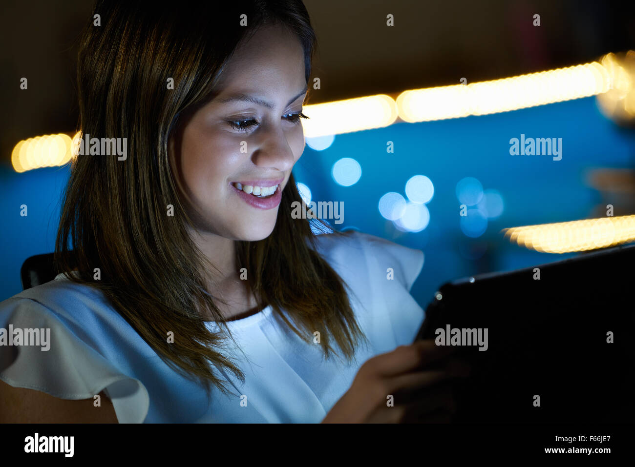 Schöne spanische Mädchen Tippen auf Touchscreen-Gerät, in der Nacht zu Hause sitzen. Die junge Frau ist auf ihrem Tablet, dann studieren Stockfoto