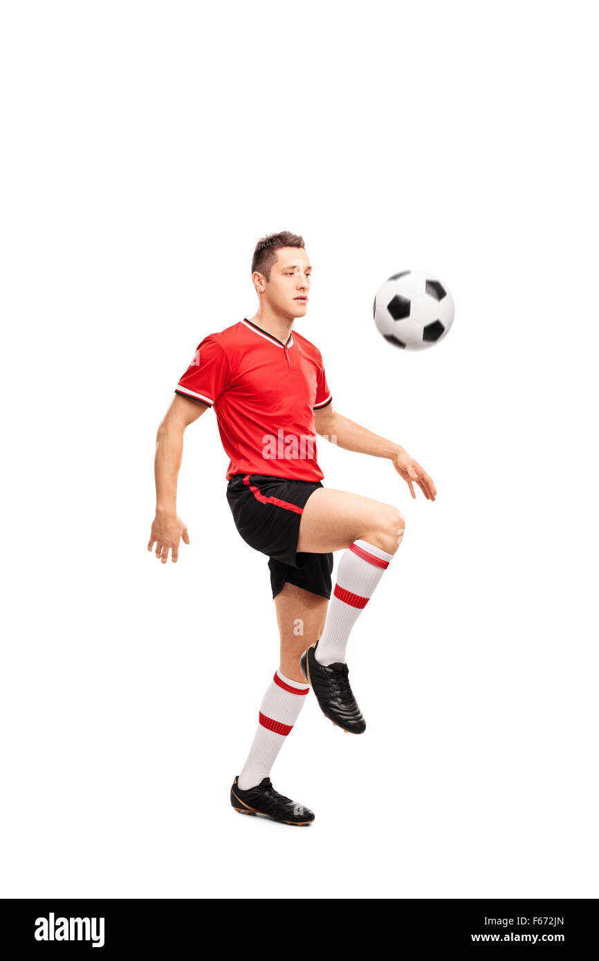 Voller Länge Porträt eines jungen Fußballspielers jonglieren einen Ball auf seinen Knien isoliert auf weißem Hintergrund Stockfoto
