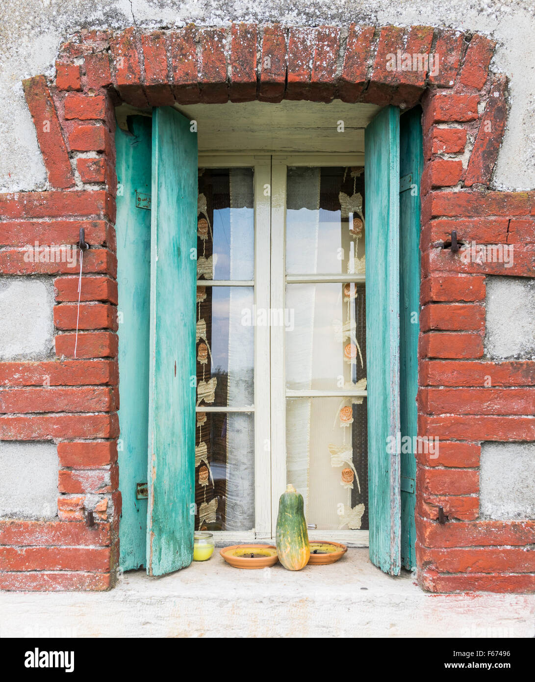 Fenster eines Bauernhauses mit Holzbalkonen und rotem Backstein Rahmen. Stockfoto