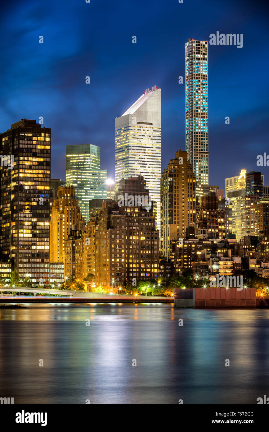 Beleuchtete Midtown Manhattan Wolkenkratzer und Lichter der Stadt spiegeln sich im East River in der Dämmerung. Skyline von New York City. Stockfoto