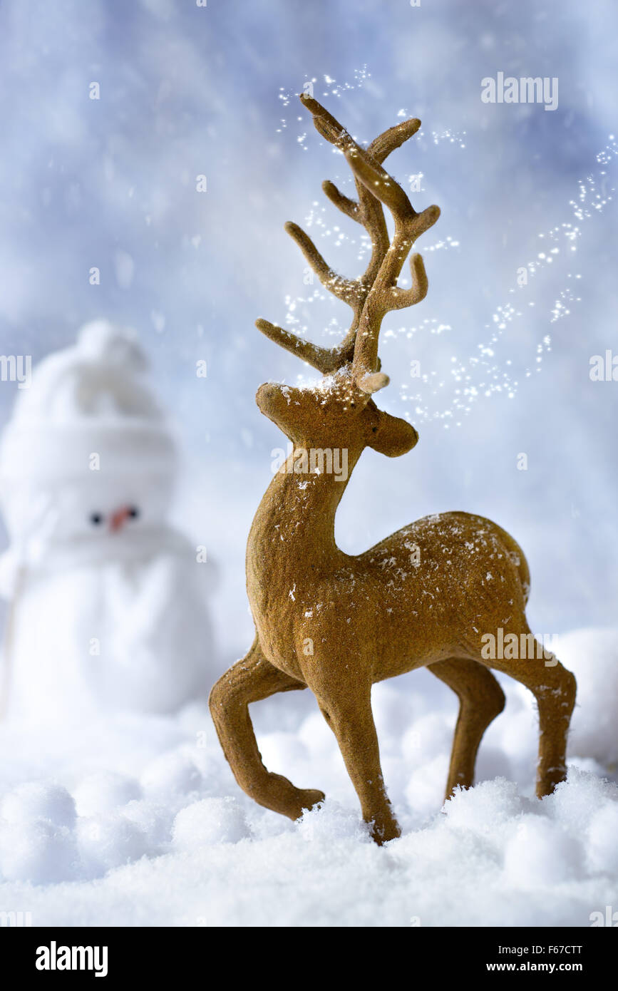 Rentier Weihnachten Figur im Schnee-Szene mit Schneemann im Hintergrund Stockfoto