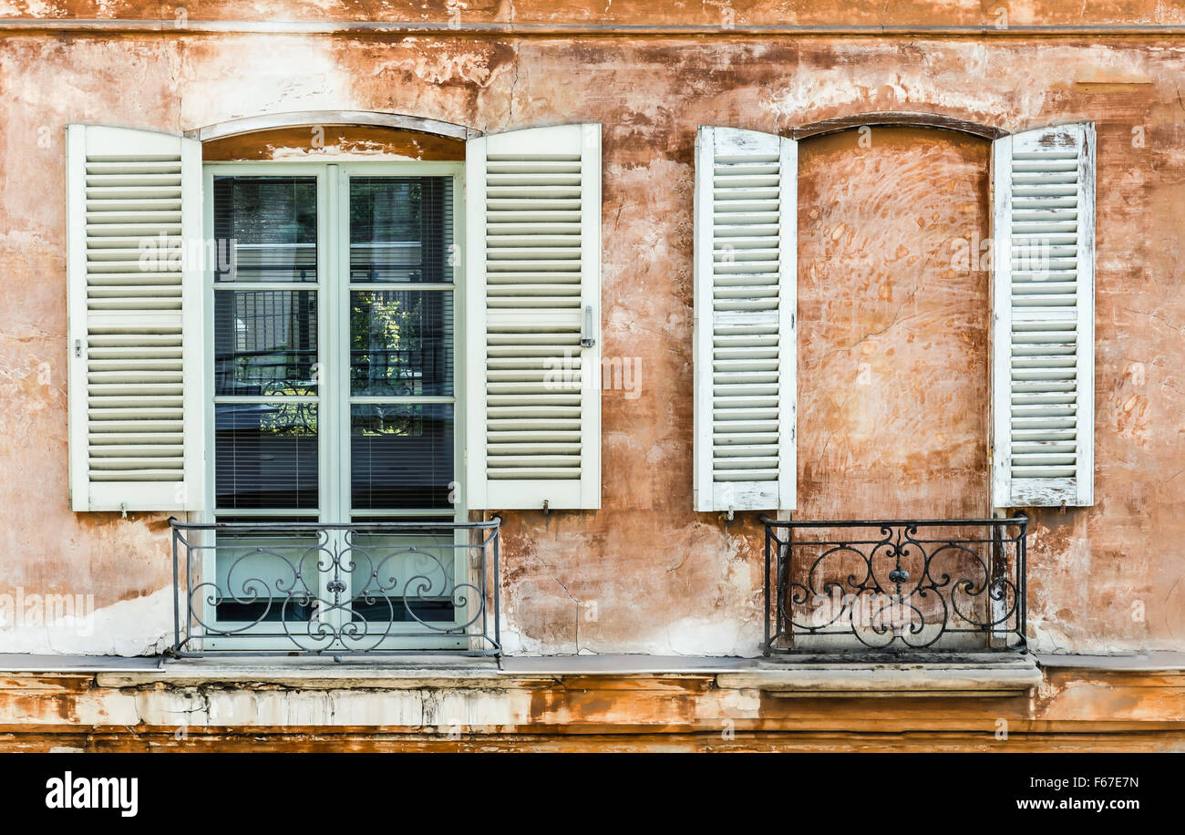 Zwei alte Fensterläden an ein Fenster und eine Mauer gebaut, um ein Fenster zu maskieren. Dekoration auf französischen Altbau. Stockfoto