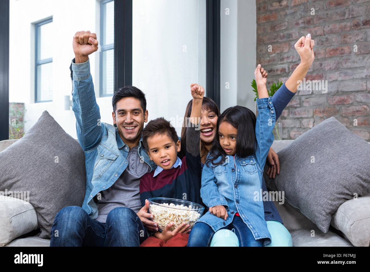 Glückliche junge Familie Essen Popcorn während des Fernsehens Stockfoto