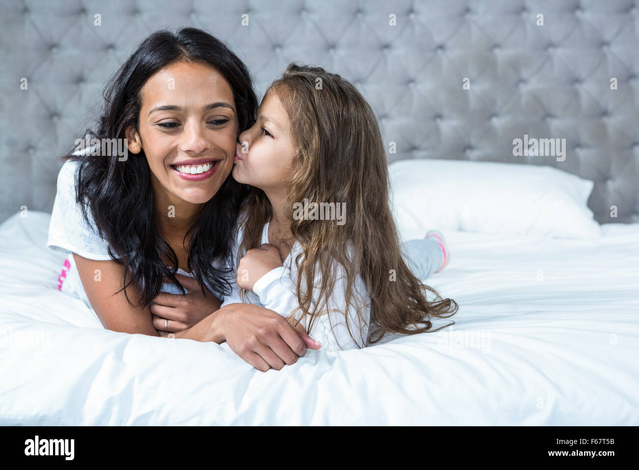 Nettes Kind küssen ihre Mutter auf dem Bett Stockfoto