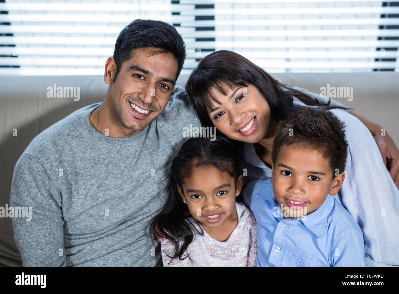 Glückliche junge Familie, die zusammen auf der Couch posiert Stockfoto