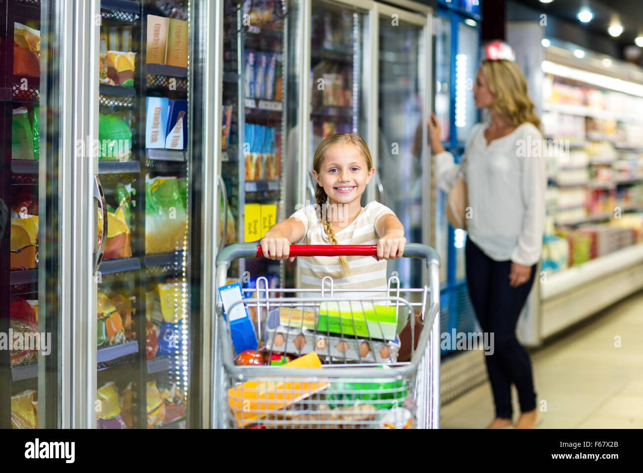 Nettes Kind Holding Einkaufswagen im Supermarkt Stockfoto