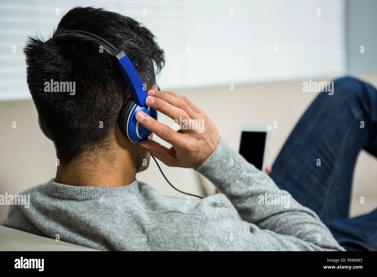 Schulter-Blick über legerer Mann Musik hören Stockfoto
