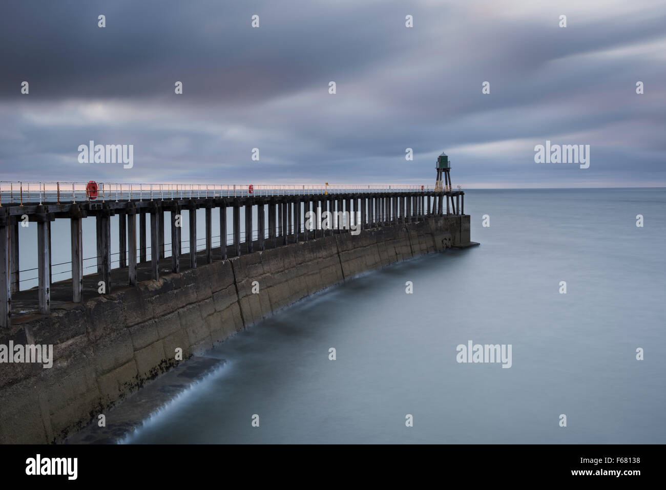 Langzeitbelichtung Schuss Whitbys Pier West, in der Dämmerung - die Blautöne des Meeres und des Himmels schaffen eine ruhige, beschauliche malerische Szene. Yorkshireküste, GB, UK. Stockfoto