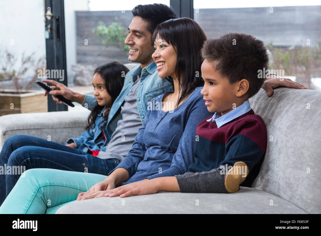 Glückliche junge Familie vor dem Fernseher Stockfoto