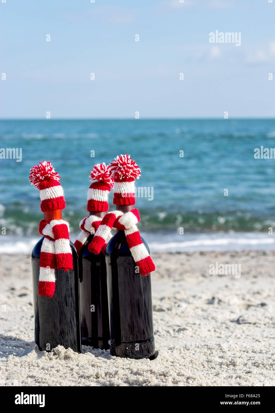 Weihnachtsgeschenke. Drei Flaschen Wein in gestrickte Mützen und Schals am Strand. Selektiven Fokus. Stockfoto