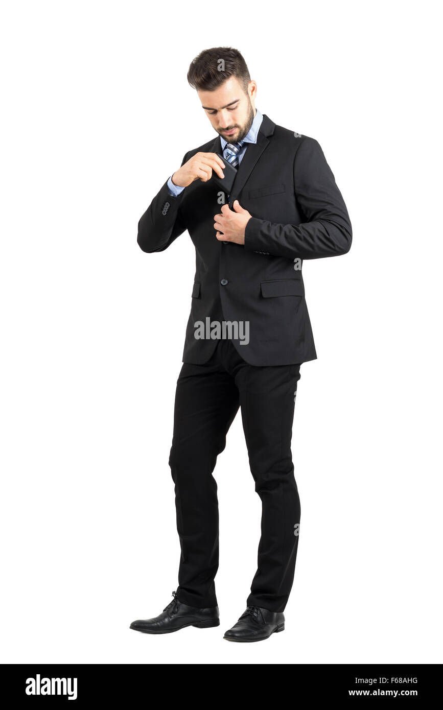 Junger Geschäftsmann setzen Handy in seinem Anzug-Jacke-Innentasche. Ganzkörper-Länge-Porträt isoliert auf weißem Hintergrund Stockfoto