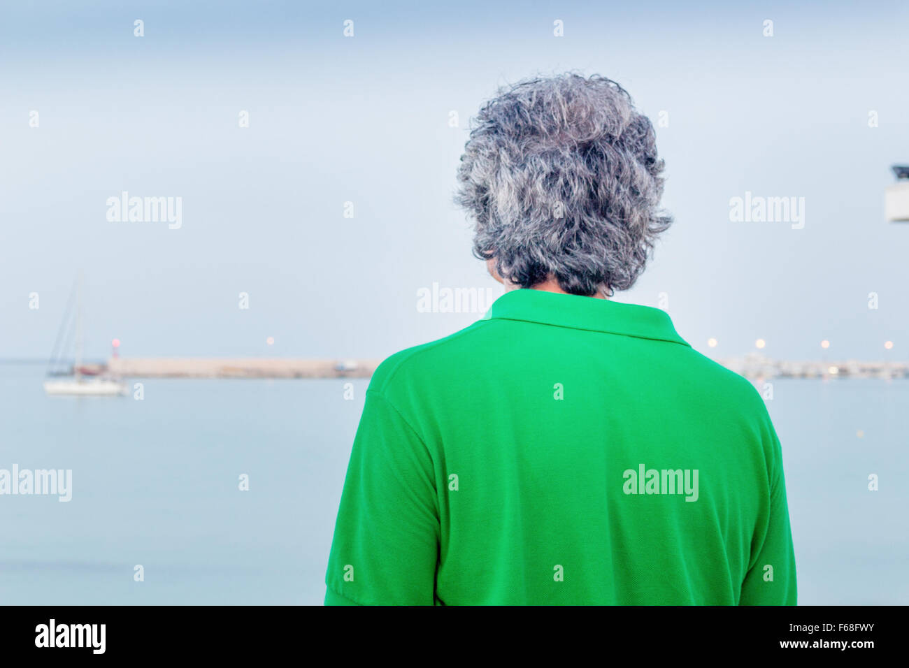 Rückseite des charmanten Mann mittleren Alters im grünen Polo in einer Stadt am Meer Stockfoto