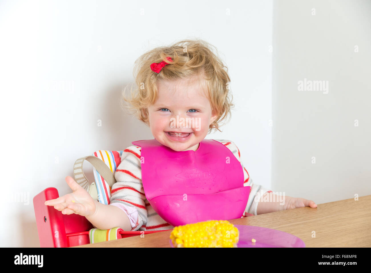 1 Jahr altes Baby lächelnd an den Esstisch, England, UK Stockfoto