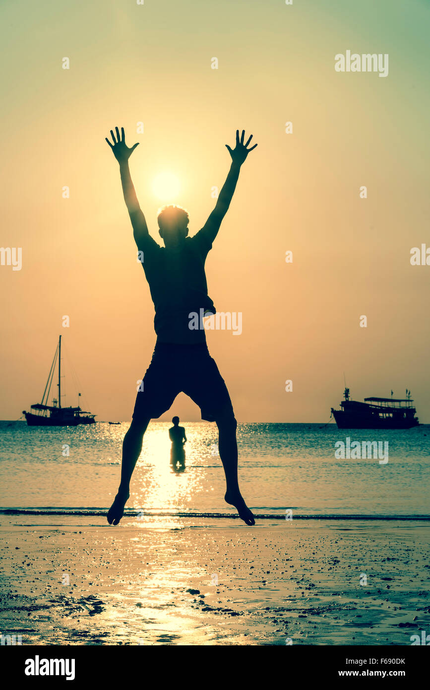 Junger Mann springt auf Strand, Silhouette, Sonnenuntergang, Koh Tao, Thailand Stockfoto