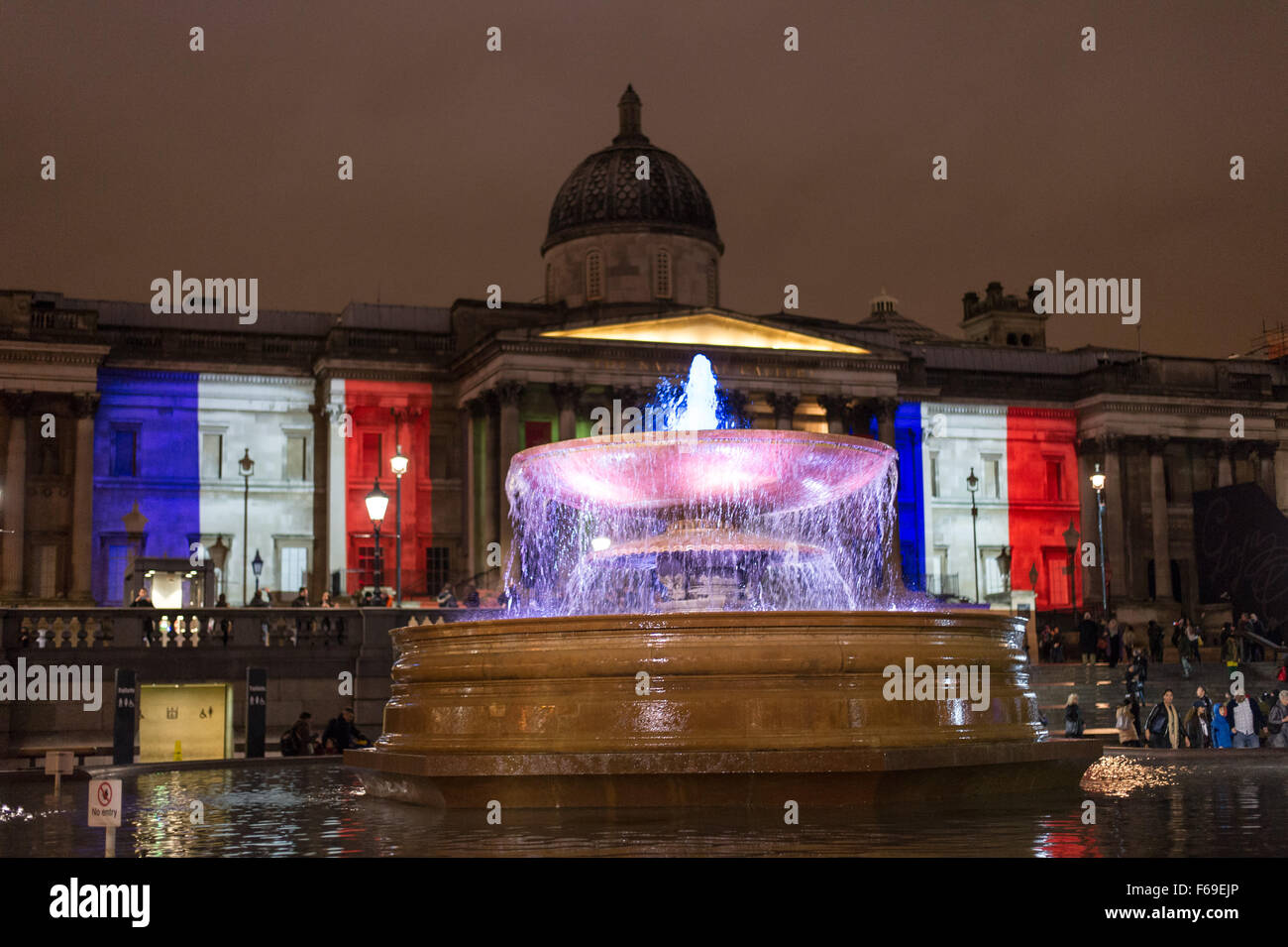 London, UK. 14. November 2015. Tausende versammeln sich am Trafalgar Square für ein Candle-Light-Mahnwache in Solidarität mit den Opfern von gestern Abend Terroristen Anschläge in Paris. Die National Portrait Gallery ist mit den Farben der französischen Tricolore Flagge beleuchtet. Stockfoto