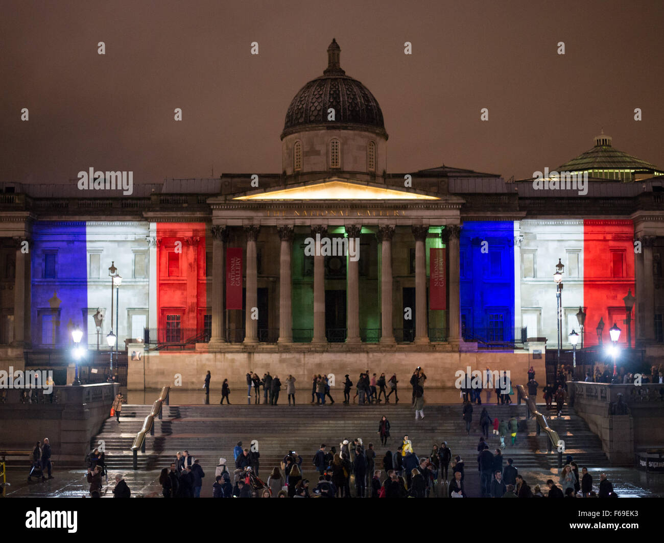 London, UK. 14. November 2015. Tausende versammeln sich am Trafalgar Square für ein Candle-Light-Mahnwache in Solidarität mit den Opfern von gestern Abend Terroristen Anschläge in Paris. Die National Portrait Gallery ist mit den Farben der französischen Tricolore Flagge beleuchtet. Stockfoto