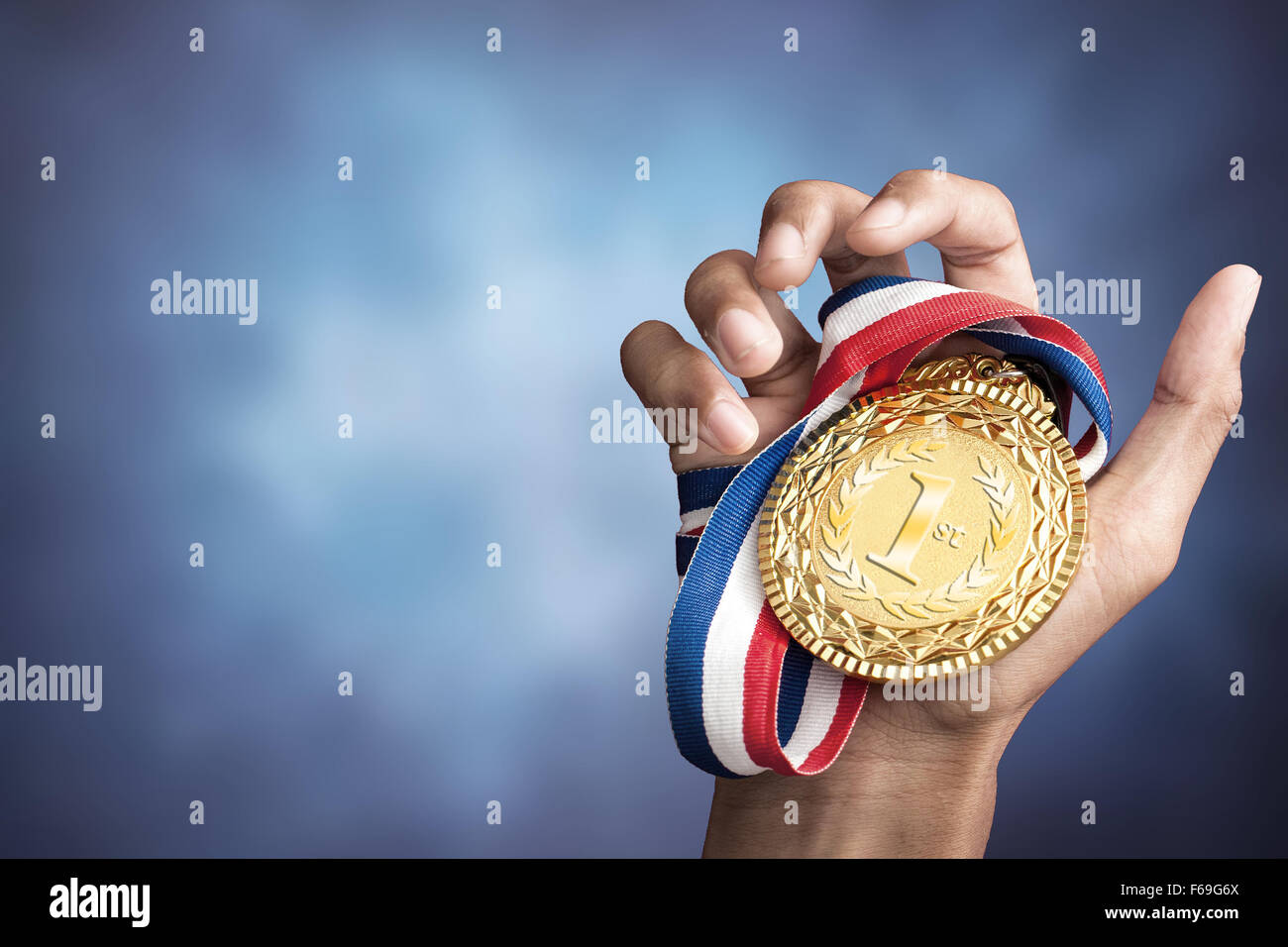 Hand hält eine Goldmedaille Stockfoto