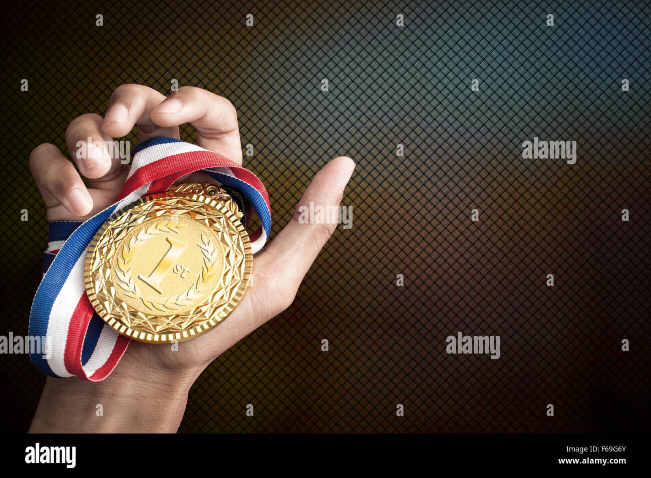Hand hält eine Goldmedaille Stockfoto