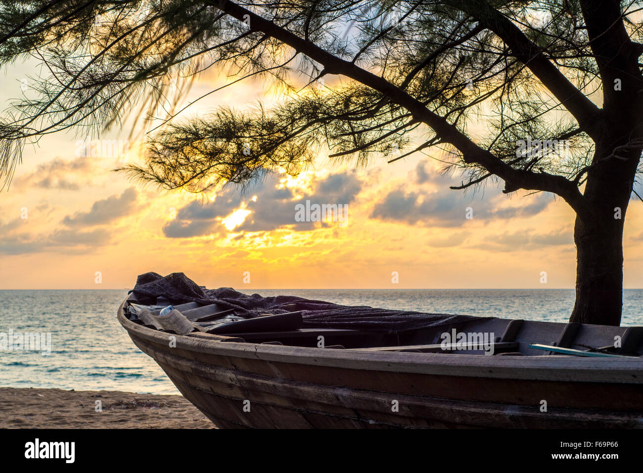 Sonnenuntergang über Mai Kao Beach in Phuket, Thailand mit Boot und Baum Stockfoto