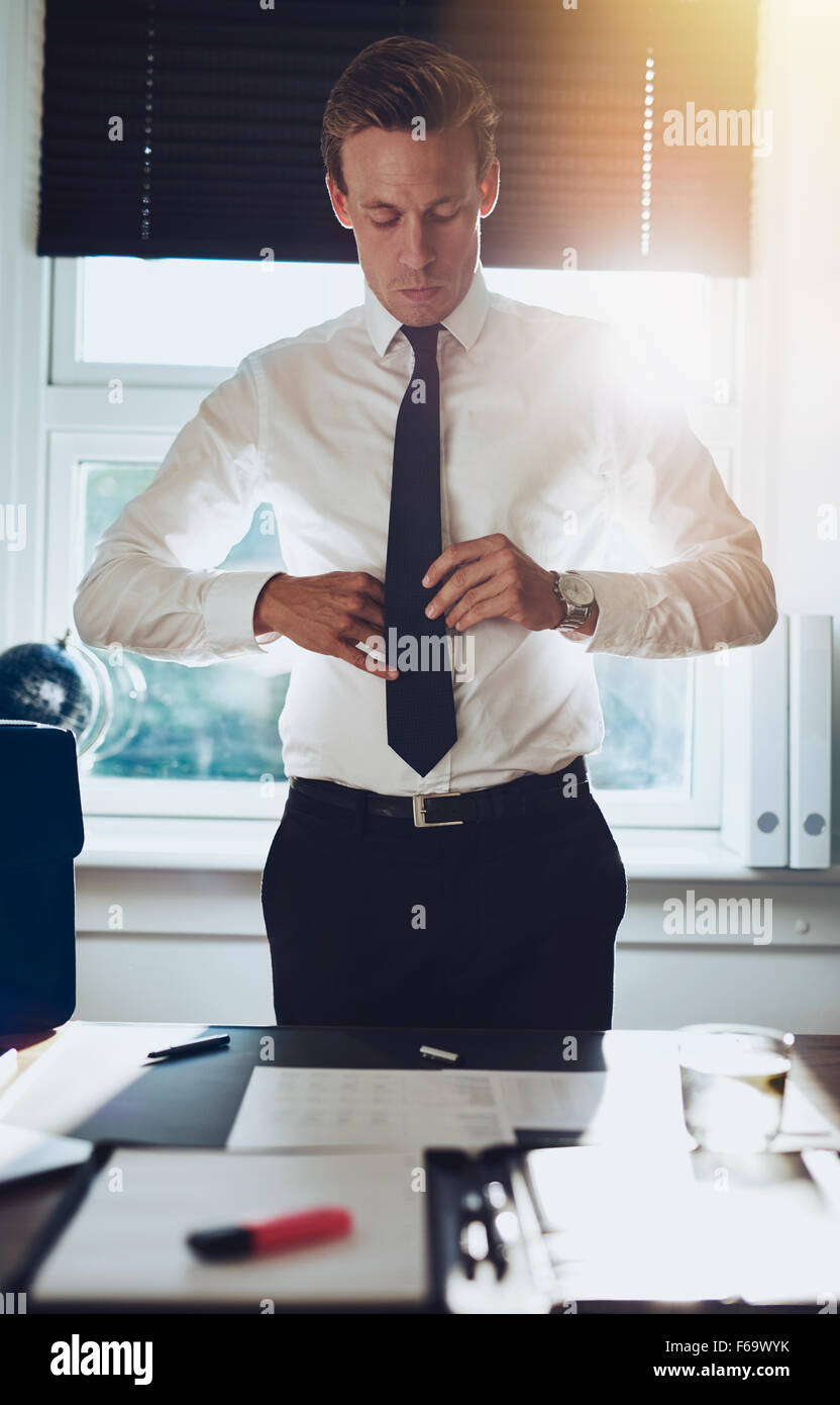 CEO Executive Business Typ weißer Mann band seine Krawatte, während am Schreibtisch in seinem Büro stehen, erfolg konzept Stockfoto