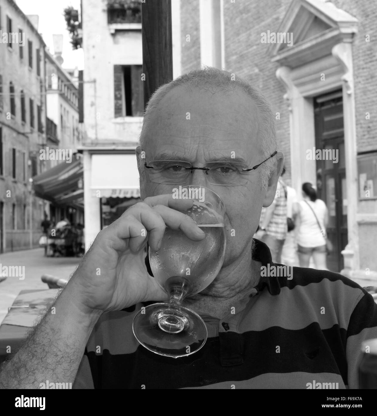 September 2015 - der ältere Engländer entspannt sich bei einem Bier in einer Bar im Freien in Venedig, Italien Stockfoto