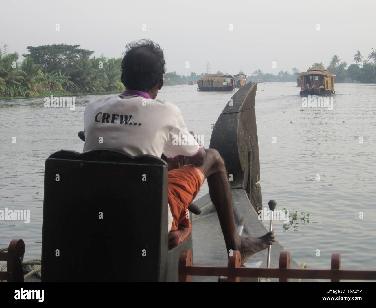 Steuermann Lenkung Hausboot mit seinem rechten Fuß a.cross die Wasserwege von Kerala, Indien Stockfoto