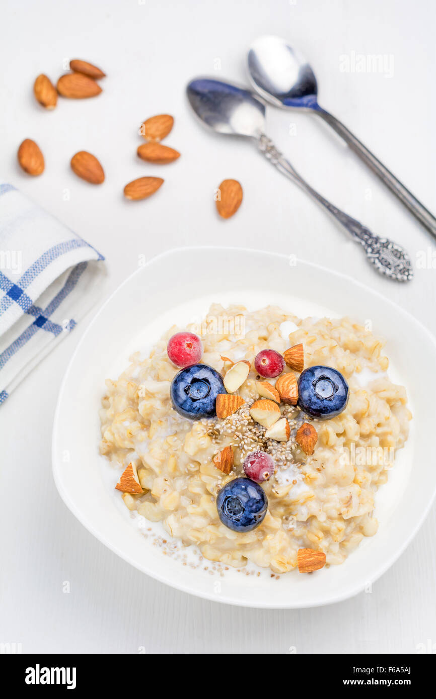 Haferflocken-Porridge mit Beeren, Chia-Samen und Mandeln in der Schale auf weißem Hintergrund, Ansicht von oben Stockfoto