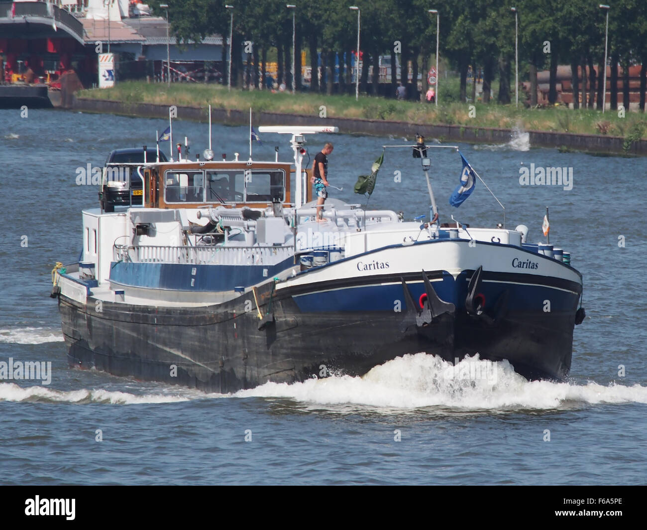 Dieses Bild des Amsterdam-Rijnkanaals zeigt ein geschäftiges Logistikzentrum mit verschiedenen Schiffen, darunter ein Containerschiff, ein Öltankschiff und einen allgemeinen Gütertransport. Er hebt den effizienten Warenverkehr über Wasserstraßen und die Bedeutung des Seeverkehrs für den Welthandel hervor. Stockfoto
